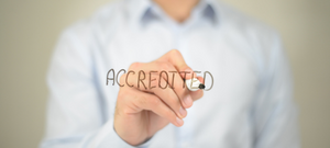 A man writing 'accredited' on a window